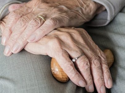 hands of an elderly person with walking stick